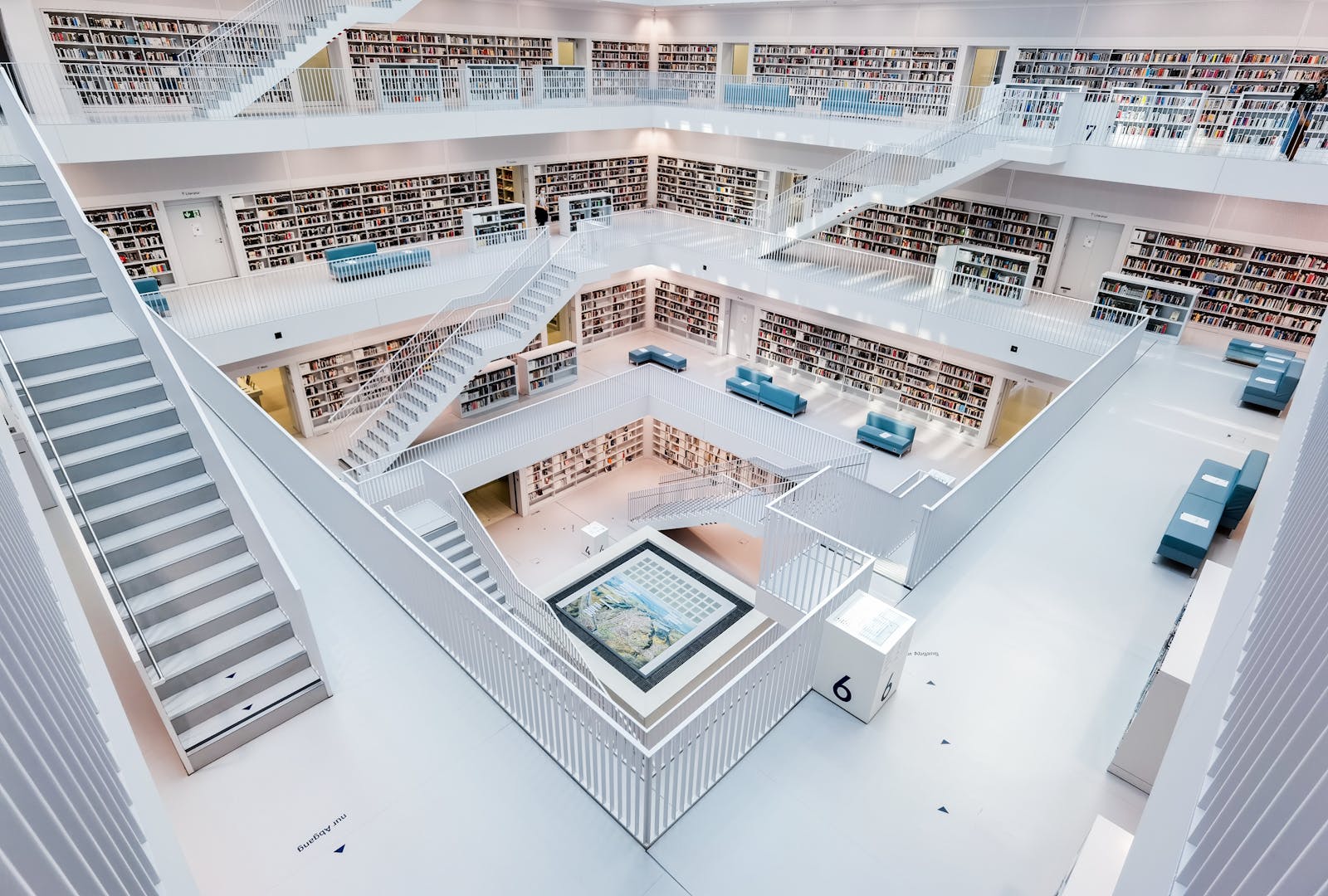 Spacious modern library with minimalist white design, abundant bookshelves and seating areas.